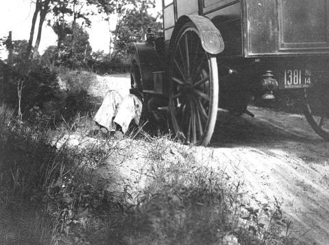 1912 Bookwagon broken down with man under wagon fixing
