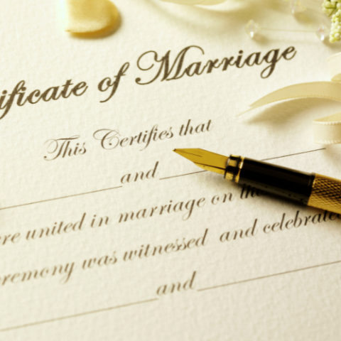 Certificate of Marriage with ink pen resting on page.