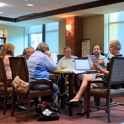 People sitting around a table in Western Maryland Room with a laptop.