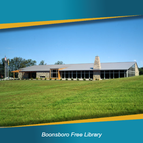 Boonsboro Free Library building with grass field in front and blue sky behind.