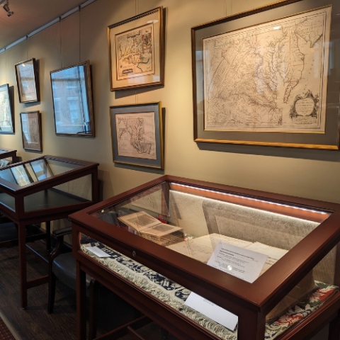 Wooden display cases along a wall with framed maps of Maryland.