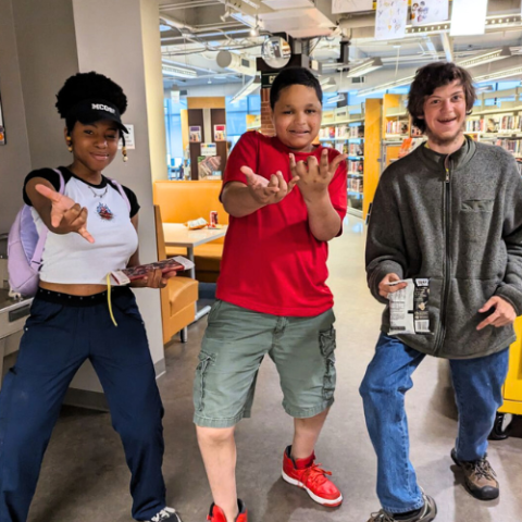 Three teens standing with arms extended like Spider Man.