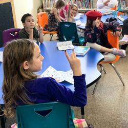 Students in a school setting sitting at blue round tables